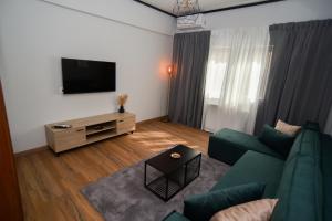 a living room with a green couch and a flat screen tv at Black and white suites 2 in Thessaloniki