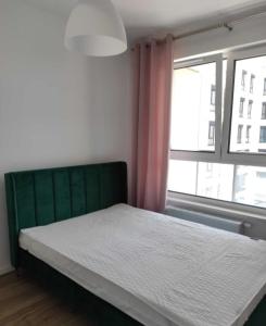 华沙Airport Apartment的一间卧室配有一张带绿色床头板的床和窗户