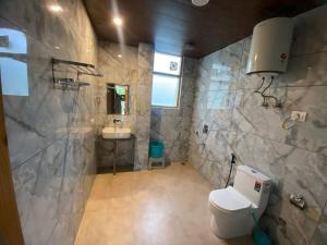 a bathroom with a toilet and a sink at Persimmon Farmstead in Manāli