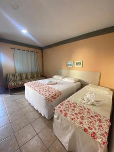 una habitación de hotel con dos camas y un sofá en Pousada e Chale Porto Paraiso, en Porto Seguro