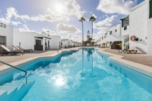 una piscina de agua azul frente a un edificio en Casa Su Lanzarote, en Puerto del Carmen