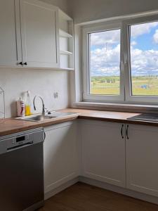 a kitchen with white cabinets and a sink and a window at Agroturystyka Grodzisko in Lidzbark
