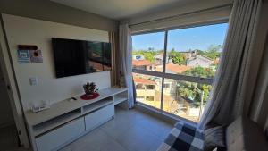 a living room with a large window and a television at Aline Duque 308 no Centro de Porto by La Playa in Porto De Galinhas