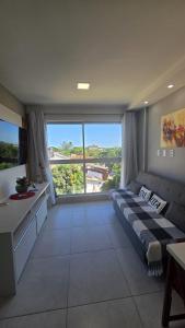 a living room with a couch and a large window at Aline Duque 308 no Centro de Porto by La Playa in Porto De Galinhas