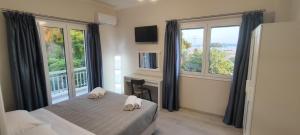 a bedroom with a bed and a desk and windows at Anna's Apartments and Studios - Planespotter's Paradise!!! in Corfu Town