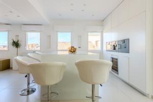 a white kitchen with white chairs and a kitchen island at Hôtel Traverse Des Artistes in Cannes