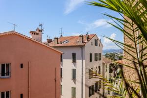 a view of buildings in a city with a palm tree at Hôtel Traverse Des Artistes in Cannes