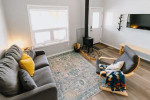 a living room with a couch and a fireplace at Eagle - Cozy tiny home with mountain views in Nordegg
