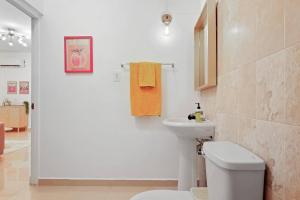 ein Badezimmer mit weißer Toilette und Waschbecken in der Unterkunft San Juan Apartment Steps Away From the Beach in San Juan + 13 Fotos