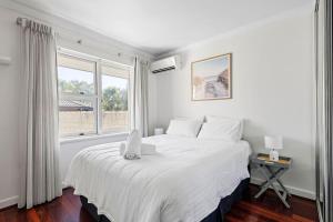 a white bedroom with a large bed with a window at Bayswater Retreat, 3 Bed house. in Perth