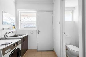 a white bathroom with a sink and a washing machine at Bayswater Retreat, 3 Bed house. in Perth +19 photos