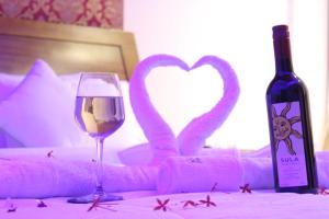 a table with a glass of wine and two pink towels at Sia Resort in Nagaon