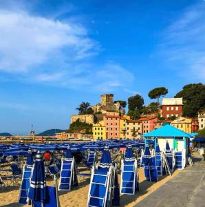 a group of blue chairs on a beach with a town at La camera a due passi dal mare in San Terenzo