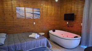 a bathroom with a tub and a bed and a tv at Pousada Pimenta Rosa - Praia do Rosa - SC in Praia do Rosa
