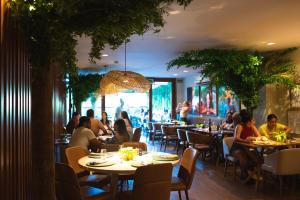 a group of people sitting at tables in a restaurant at Canto Hotel in Salvador