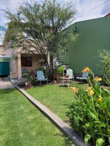 einen Garten mit Stühlen, einem Tisch und einem Baum in der Unterkunft Departamentos serranos - Menta y Peperina in La Falda