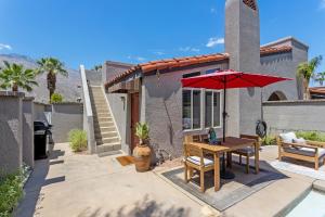 a patio with a table and a red umbrella at Caballeros by ACME House Company in Palm Springs