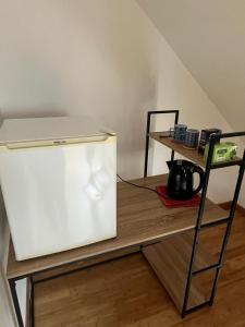 a white refrigerator sitting on a table next to a shelf at Maison proche Circuit des 24h du Mans in Saint-Gervais en-Belin +1 photo