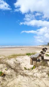 a bench sitting in the sand on a beach at Casa Beira-mar da Sumaré in Balneário Gaivotas +15 photos