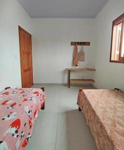 a bedroom with two beds and a table in it at Casa Beira-mar da Sumaré in Balneário Gaivotas