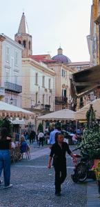 a woman walking down a street in a city at Antica Dimora DE FERRERA - Alghero in Alghero