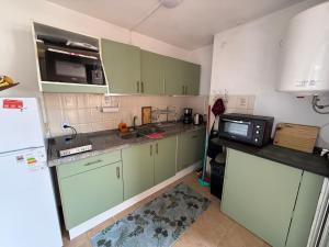 a kitchen with green cabinets and a microwave at MAPAR Apartamento 2 dormitorios en Montevideo in Montevideo