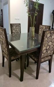 a dining table and two chairs with a glass table and chairs at Shelton Royal Hotel in Multan