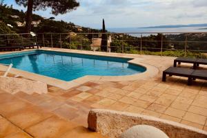 a swimming pool with a bench on a patio at Villa Luxe avec Vue sur Saint-Tropez, Roquebrune in Roquebrune-sur-Argens