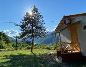 a house with a tree next to a building at Kontsikho Cottage in Mukhli, Ambrolauri in Mukhli