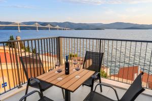a table and chairs on a balcony with a view of the water at Apartments Sunset Komarna in Komarna