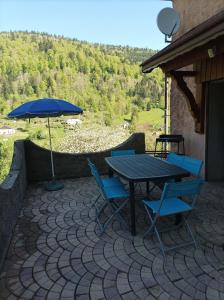 a patio with a table and chairs and an umbrella at Le refuge de la source in Bussang