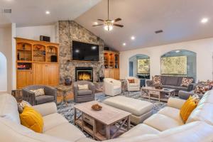 a living room with white furniture and a stone fireplace at Big Oak Manor w/movie theater, hot tub, sleeping for 20! in Oakhurst