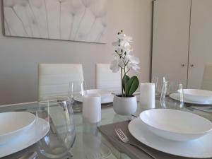 a glass table with white dishes and a vase with white flowers at Villetta Rewal in Rewal +14 photos