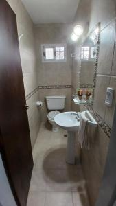 un bagno con un water e un lavandino di CASA TODA EN PLANTA BAJA CON PARQUE y PILETA INDIVIDUAL SOBRE ASFALTO A POCAS CUADRAS DEL CENTRO DE MERLO a Merlo