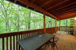 un porche cubierto con mesa y sillas en 4 Mi to Lake Wooded Log Cabin in Eureka Springs!, en Eureka Springs
