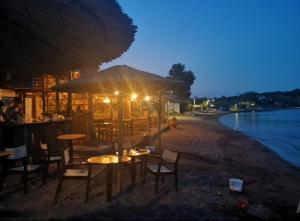 a restaurant with tables and chairs on the beach at night at Seaside Apartment in Tsonia in Tsonia