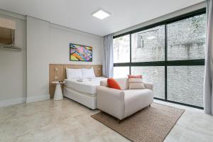 a bedroom with a white bed and a couch at Piscina com Vista Mar | WI-FI 200mb #CAC01 in Florianópolis