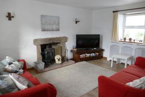 un salon avec un canapé rouge et une cheminée dans l'établissement Carol Cottage, à Kilkeel