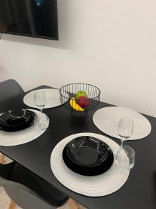 a black table with two plates and two wine glasses at Kyklamino Apartment in Loutra Oraias Elenis