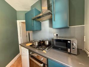a small kitchen with blue cabinets and a microwave at A3-1st Floor 2 Bed Flat near Elephant and Castle in London