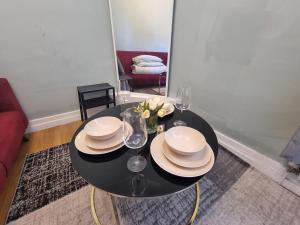 a black table with plates and glasses and flowers on it at A3-1st Floor 2 Bed Flat near Elephant and Castle in London