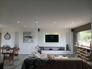 a living room with a couch and a tv on the wall at T4 Villa SOTTA entre mer et montagnes in Sotta