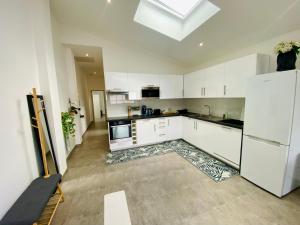 a large kitchen with white cabinets and a skylight at La maison Arkéa Aréna est climatisée avec ménage, draps et serviettes inclus in Floirac