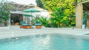 a swimming pool with two chairs and an umbrella at Casa Niza - Colonial house in Cartagena de Indias
