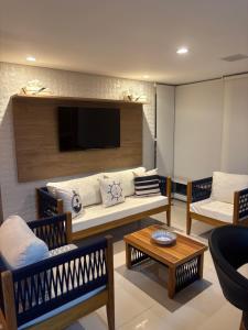 Apartamento Alto Padrão في غوارويا: غرفة معيشة مع أريكة وتلفزيون