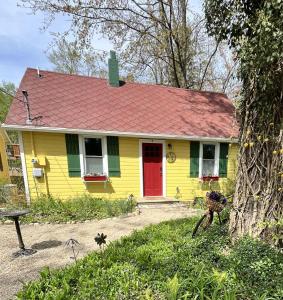 a yellow and green house with a red door at Maplewood Cottages 2 in Coloma