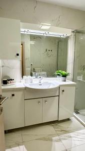a white bathroom with a sink and a mirror at Marko's Place in Hanioti