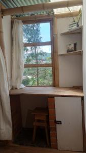a room with a desk with a window and a stool at Hospedaje Rural La Trinchera Mirador a la montañas Cerro Azul Trujillo in Trujillo
