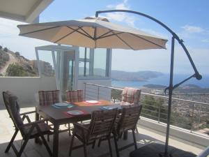 a table and chairs with an umbrella on a balcony at Viva B&B in Anavyssos