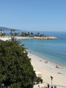 a beach with people on the sand and the water at Lisa Apartment in Menton